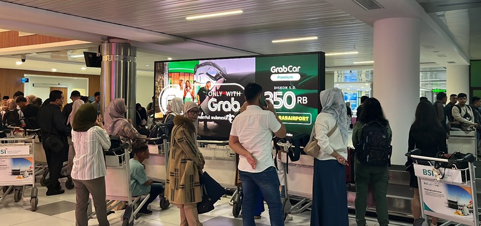 klan GRAB di layar LED di atas konveyor bagasi Bandara Internasional Hang Nadim Batam, ditayangkan oleh The Perfect Media dalam kampanye DOOH kreatif